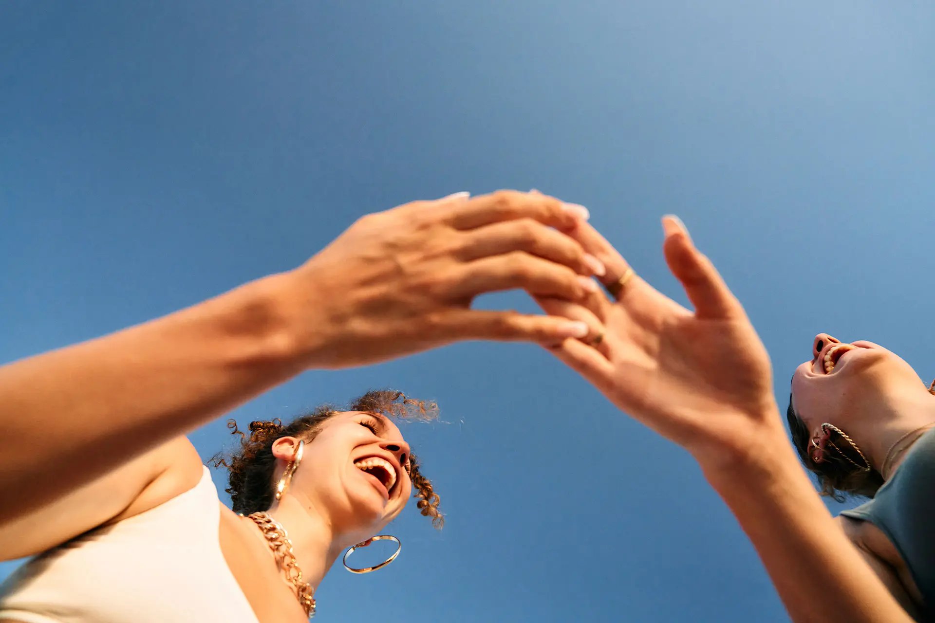 Two women laughing and touching eachothers' hands