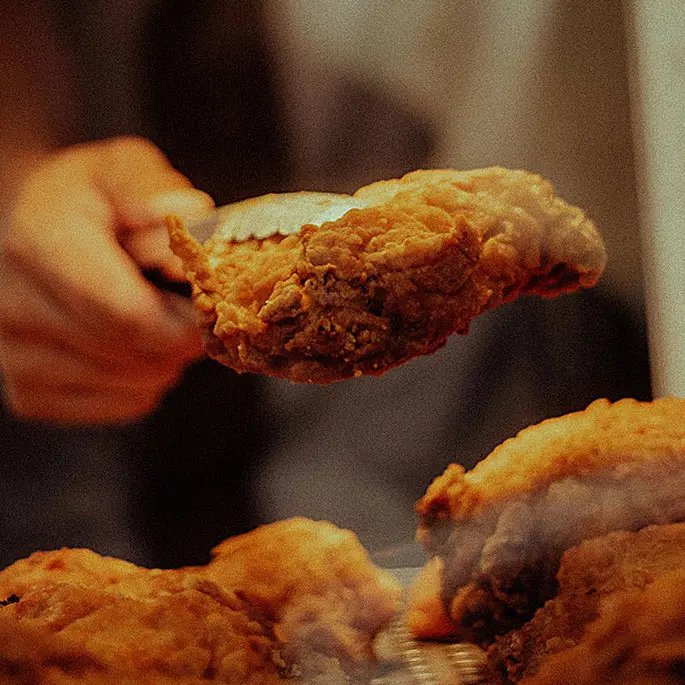Someone holding a piece of fried chicken