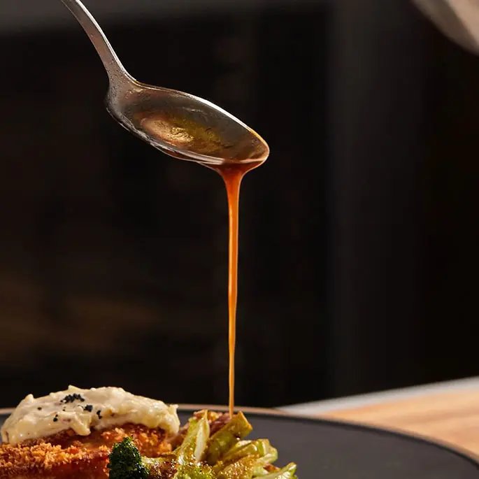 Pouring a sauce from a spoon on a dish